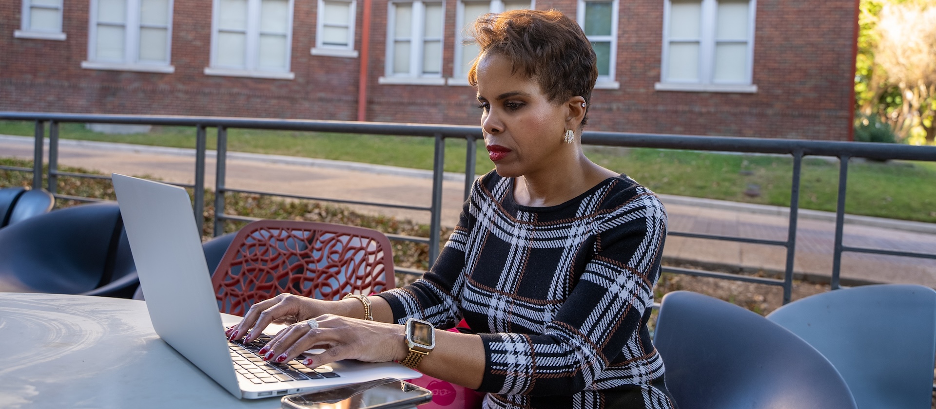 Female student outside working on a laptop.
