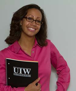SPS Student smiling infront of a white board holing a SPS notebook