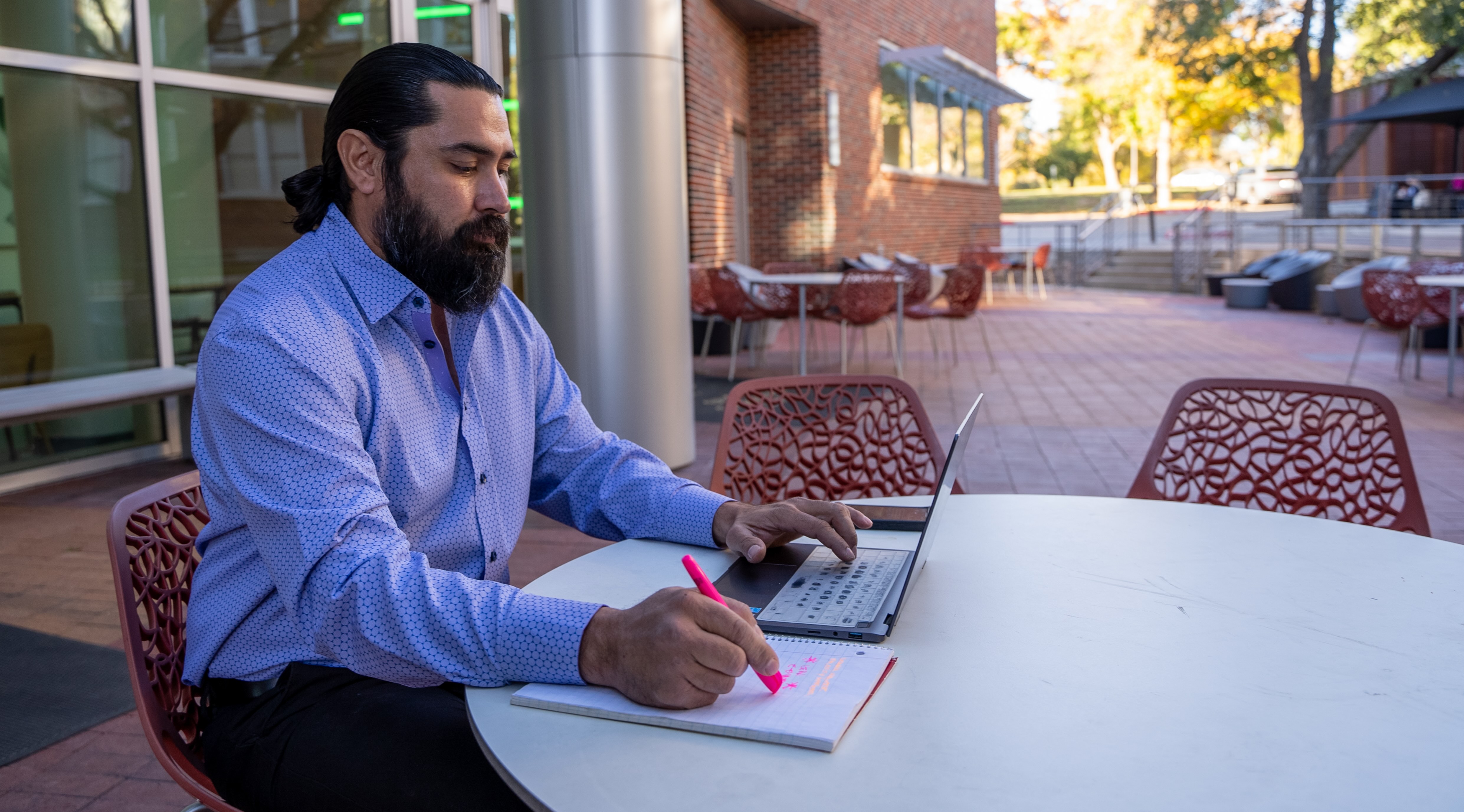 Male student on laptop sitting outside