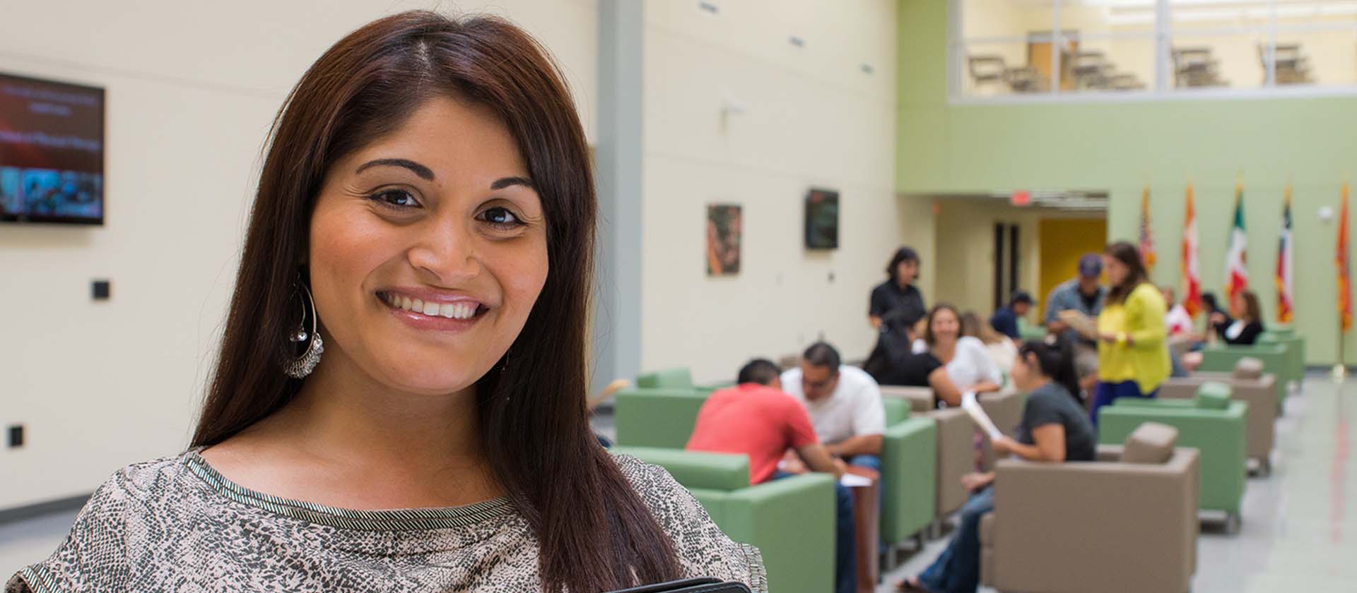 photo of woman smiling to the camera as people sit in the background to her left