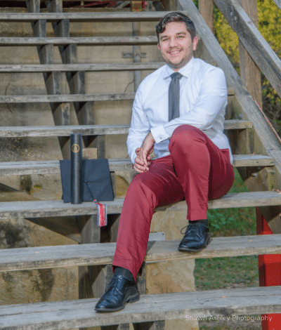 Justin Clark graduation photo at UIW sitting on the steps.