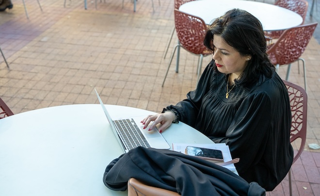 Student sitting outside working on laptop.